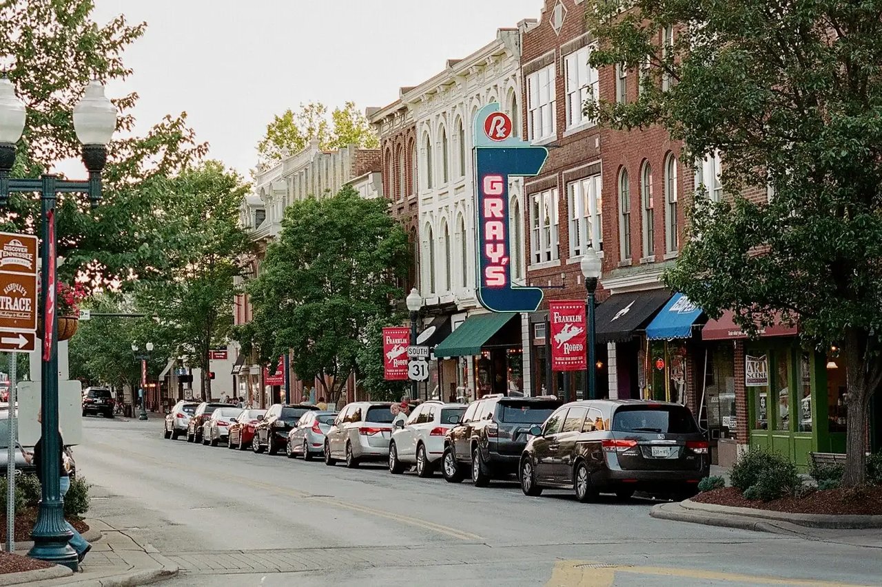 Downtown Franklin storefronts with the GRAYS sign and cars parked along a tree-lined street.