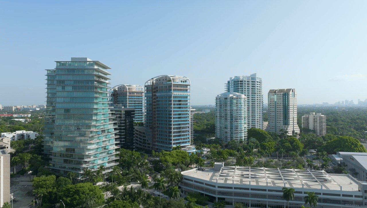 Aerial view of modern condominium towers above Coconut Grove’s tree canopy.
