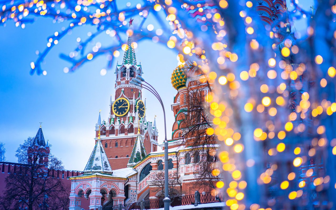 Moscow Kremlin towers and onion domes framed by glowing festive lights.
