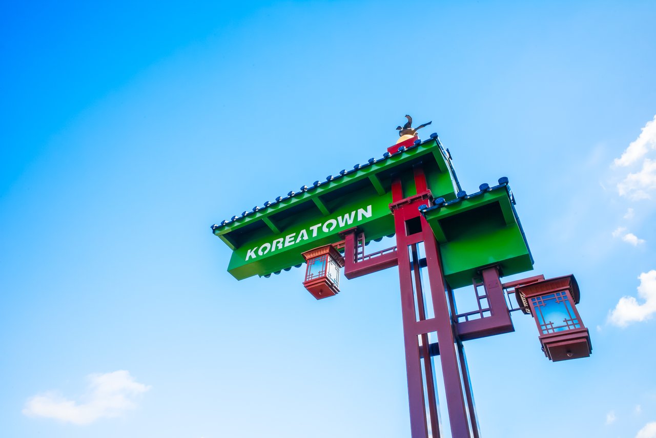 Koreatown sign against a blue sky, with a bird perched on top.