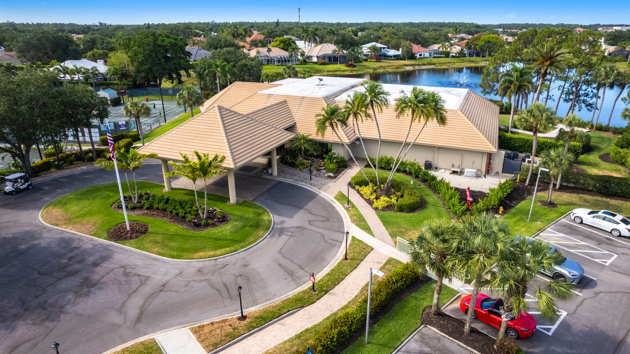 Front view of Longshore Lake clubhouse with tropical landscaping and circular driveway