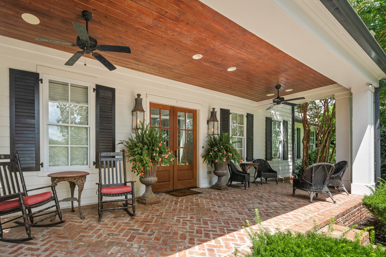Covered brick porch at 5566 Hill Rd — seating area with ceiling fan