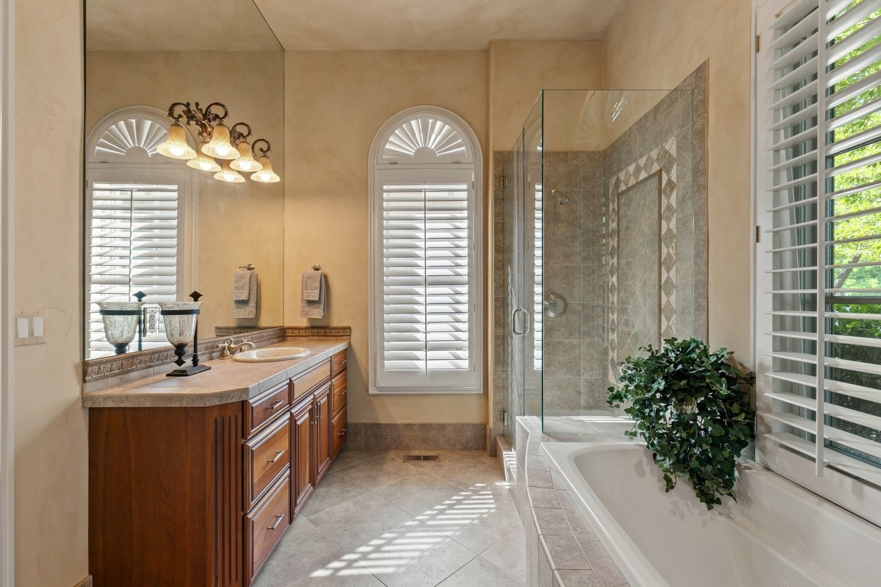 Guest-house bathroom with a dark wood vanity, glass shower, and large soaking tub.
