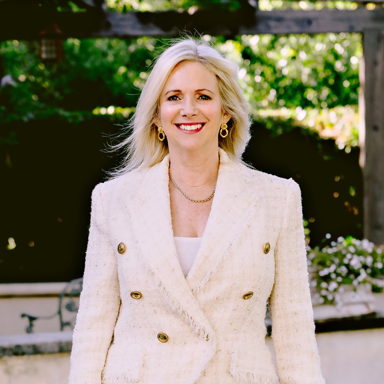Christine Christiansen smiling in a white double-breasted jacket outdoors.