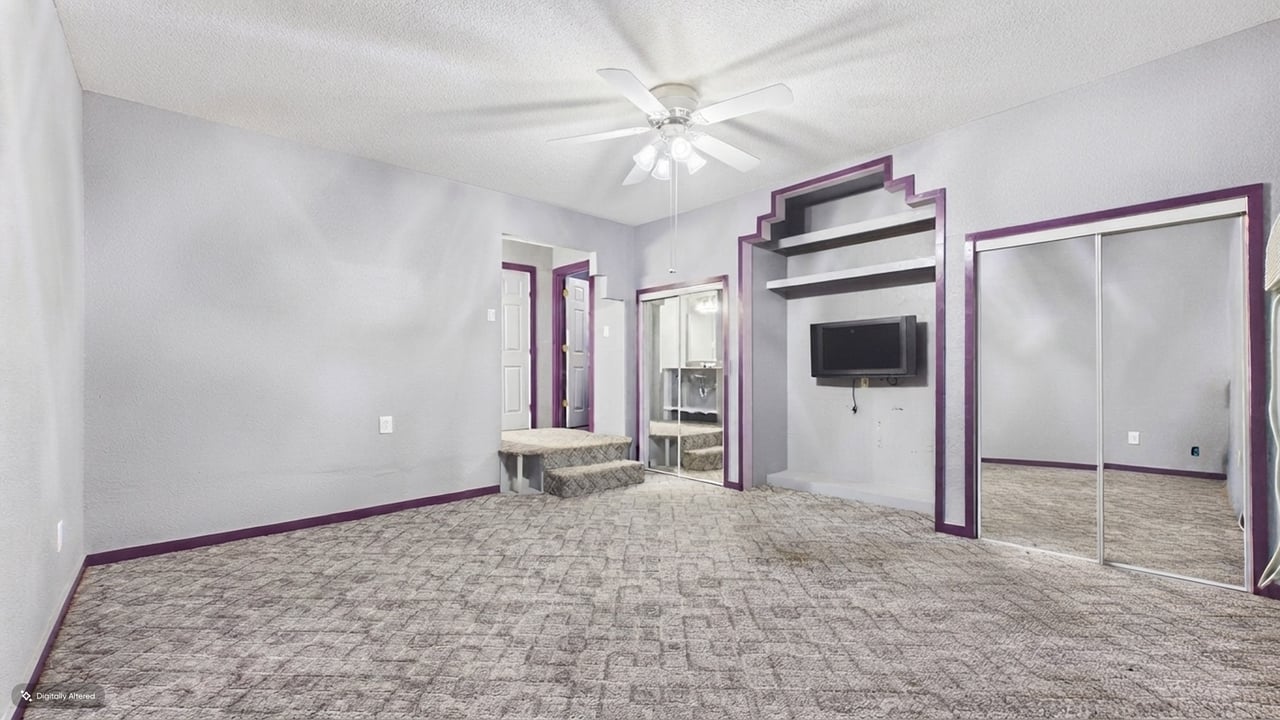 Empty bedroom with mirrored closet doors, purple trim, and a built-in TV alcove.
