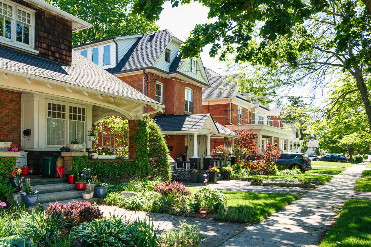 South Riverdale street lined with brick homes, leafy trees, front gardens, and a sidewalk.