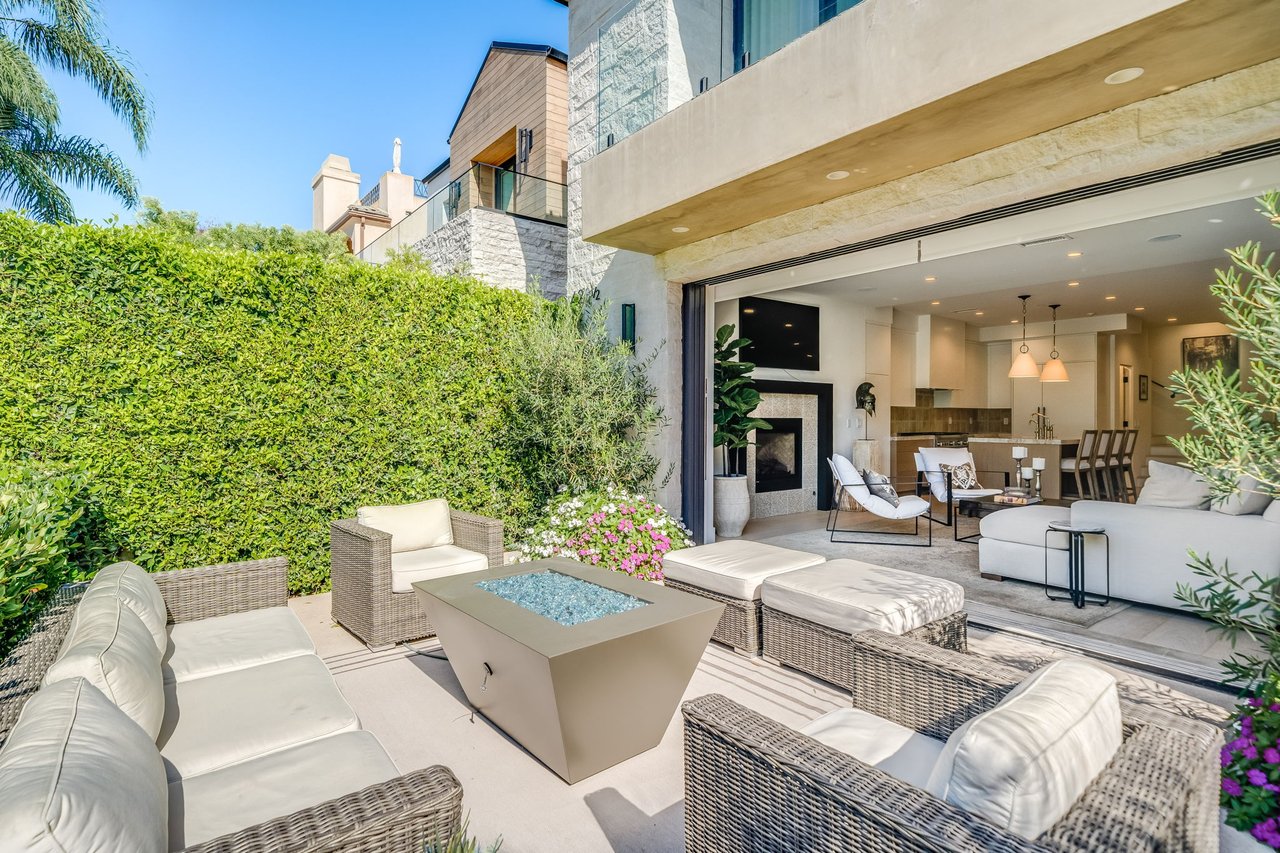 Furnished patio with wicker seating and fire table opens into a bright living room and kitchen.
