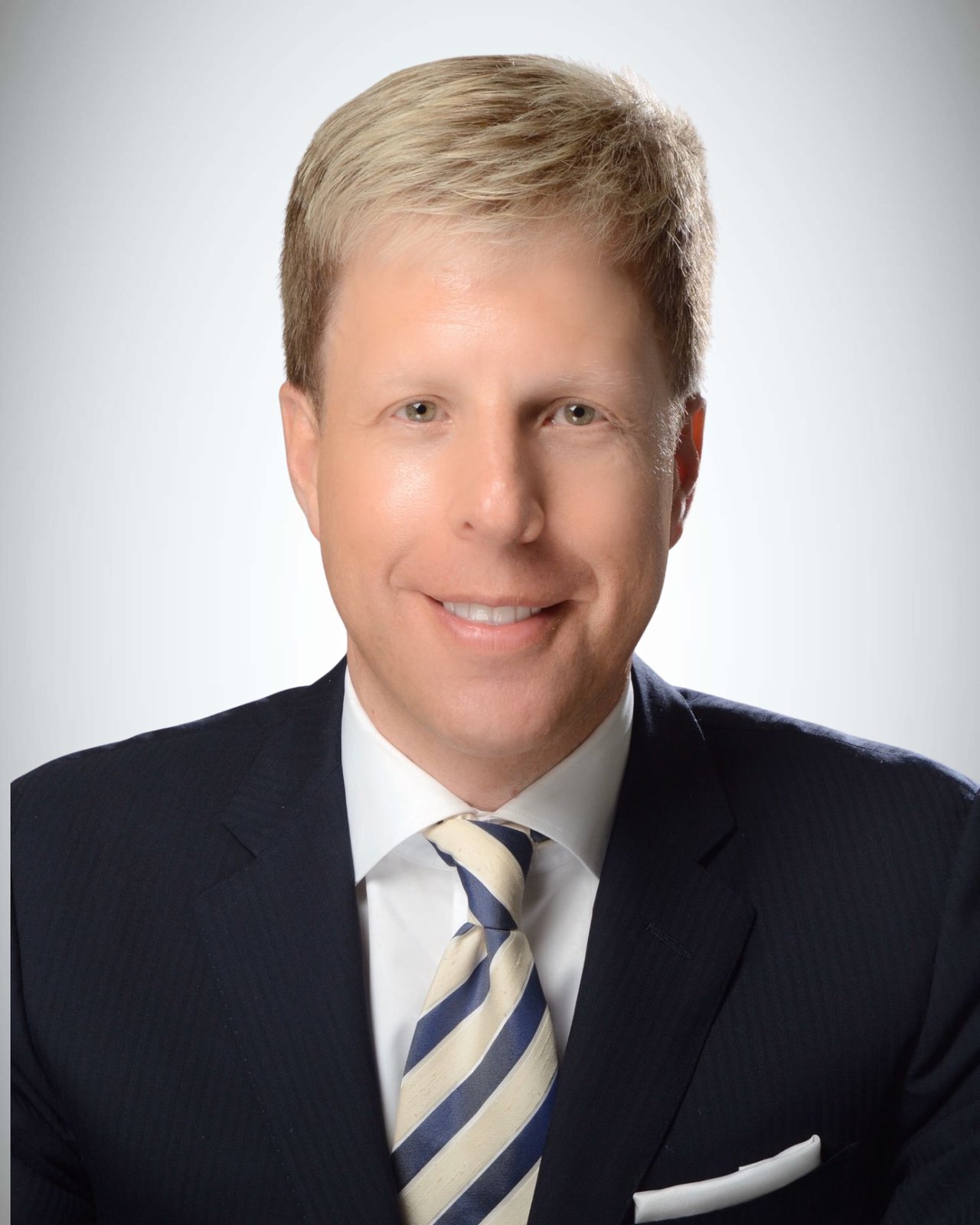 Charles Von Willerding in a dark suit and blue-and-cream striped tie.