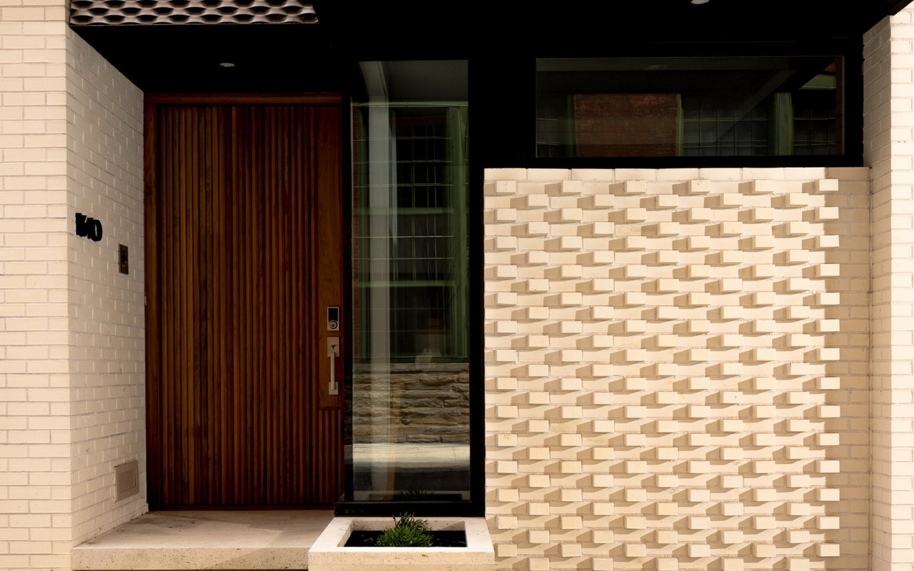 Modern home entrance with a tall slatted wood door and sculptural cream brickwork.