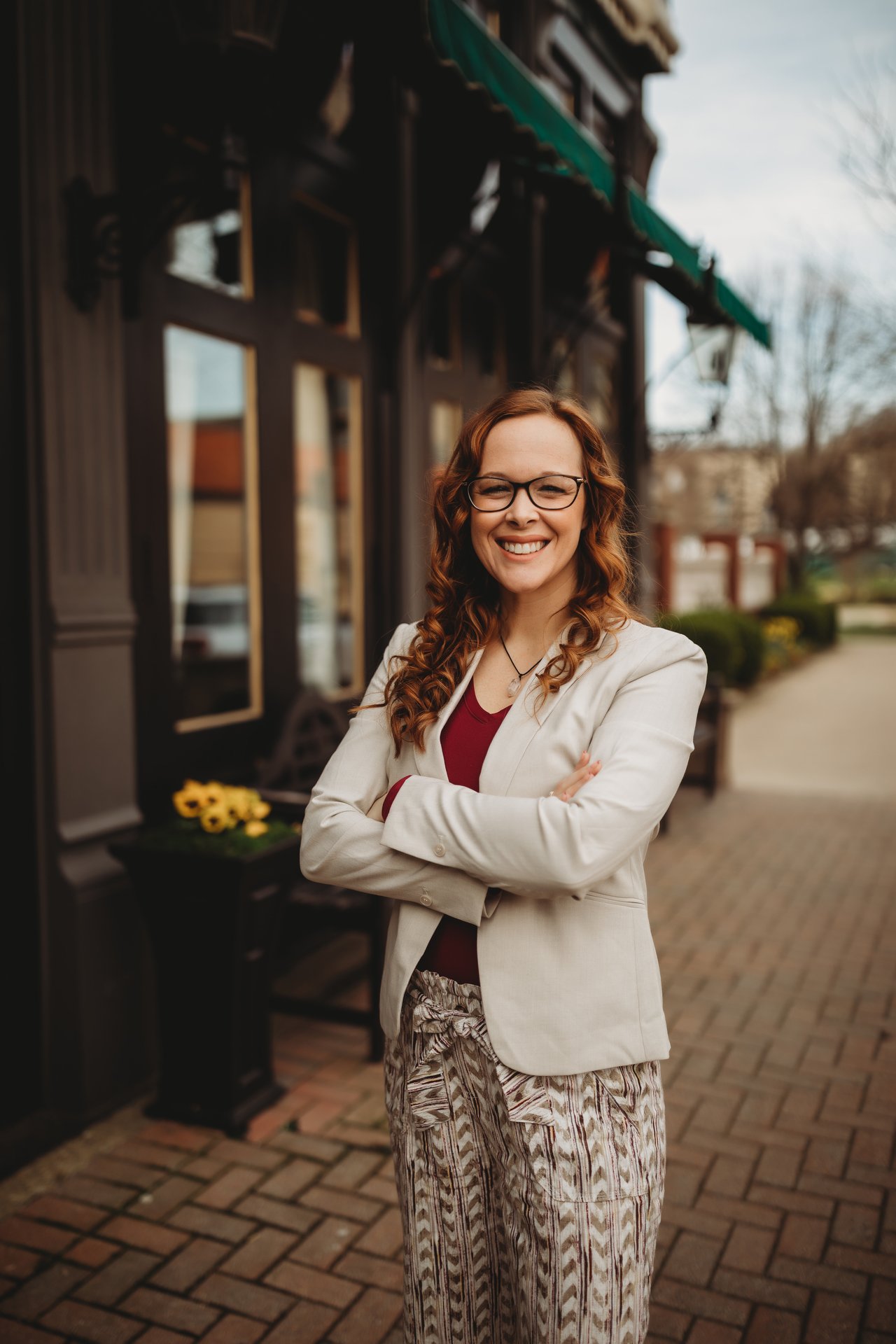 Victoriea Spiroff stands smiling with folded arms outside a storefront.