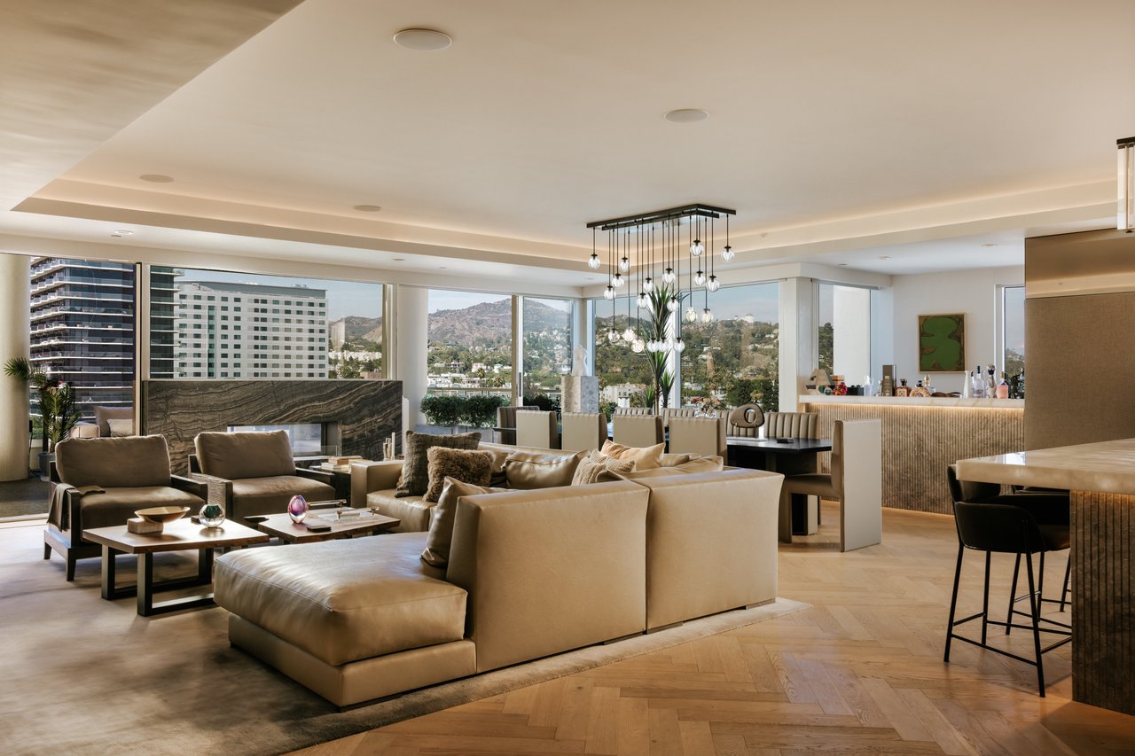 Luxury living room with cream sofas, a marble fireplace, and floor-to-ceiling windows overlooking the city.