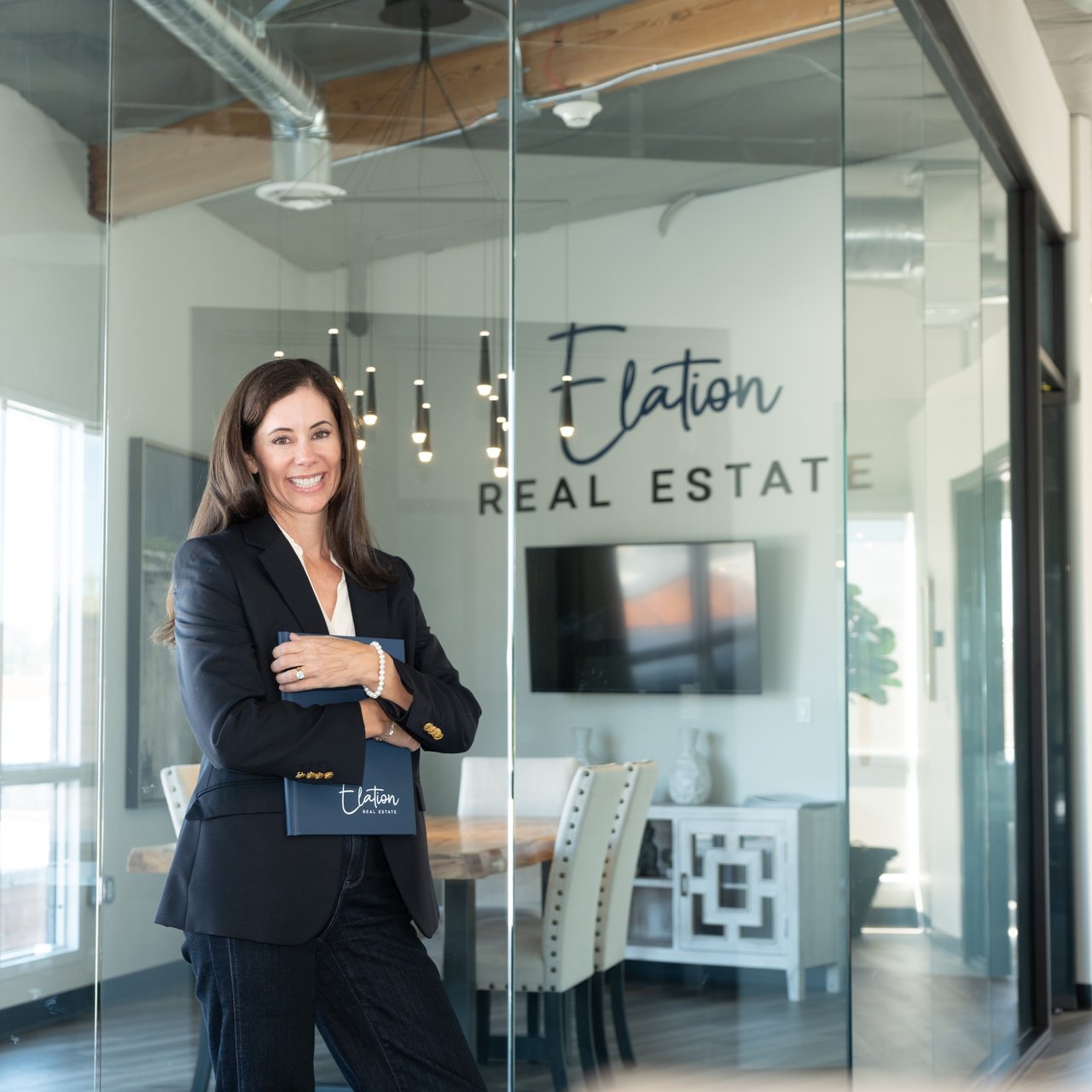 Elation Real Estate agent standing in her office in front of the company name.