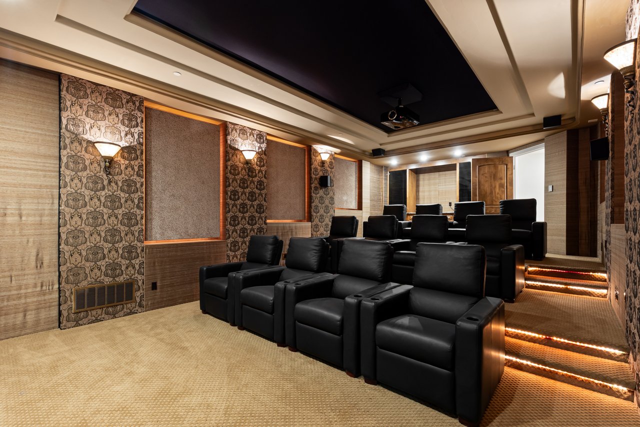 Home theater with rows of black leather recliners and illuminated steps.