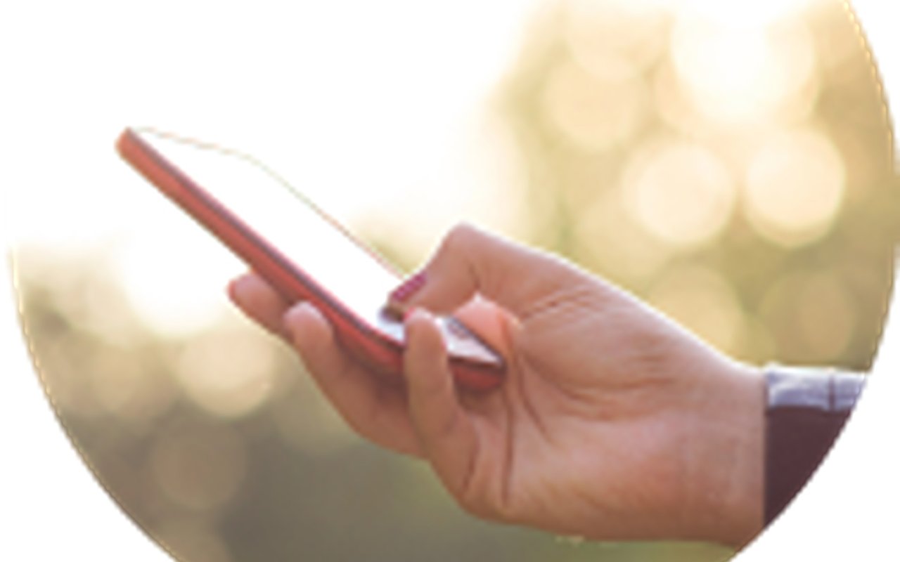 Hand holding a red-cased smartphone against a bright, blurred background.
