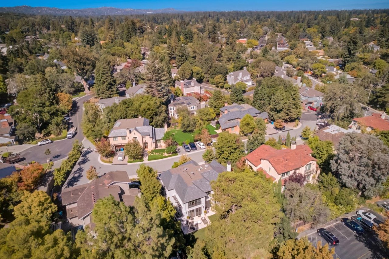 Aerial view of a tree-lined residential neighborhood in Menlo Park, California, with homes, streets, and the surrounding hills visible in the distance.