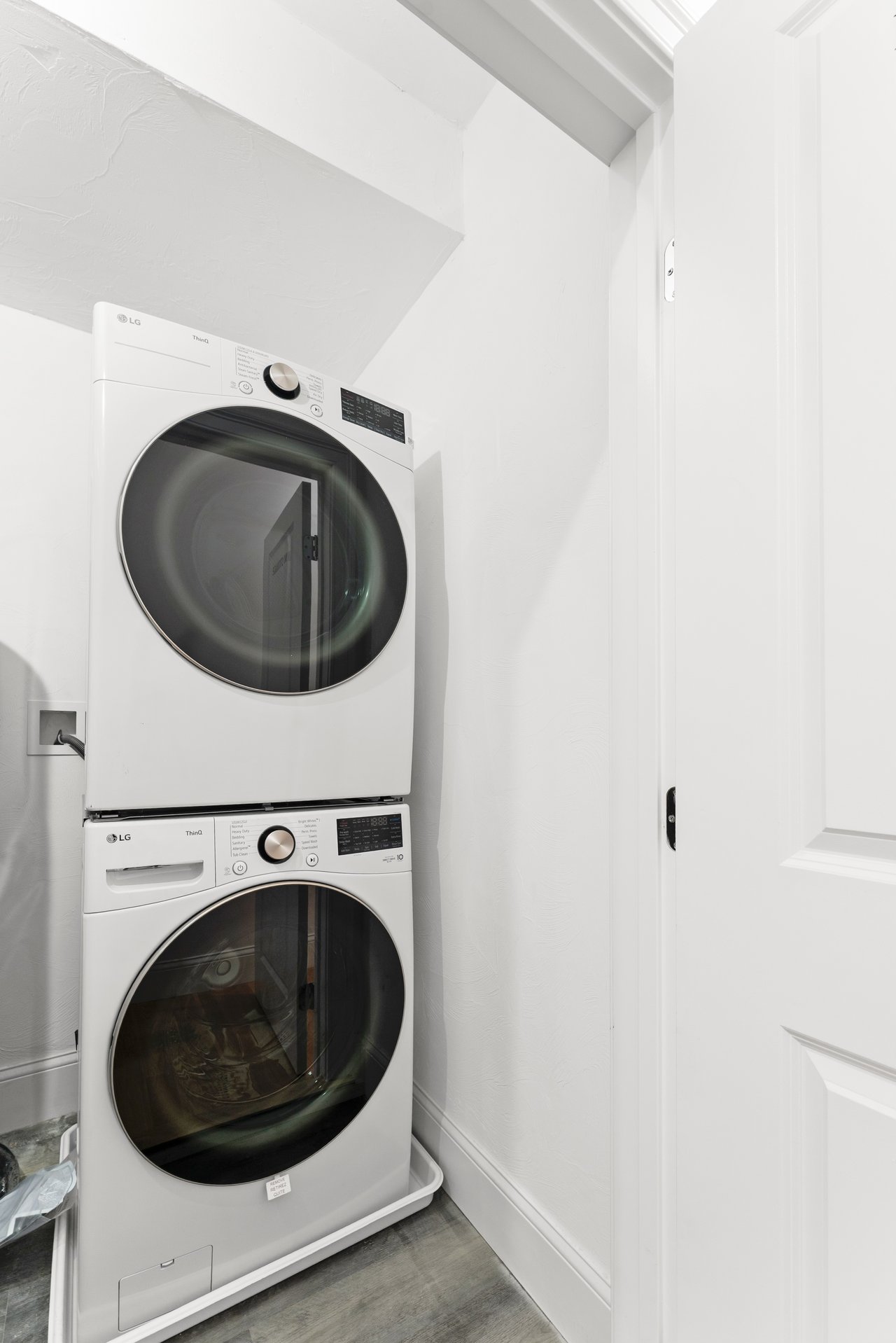 Stacked white LG washer and dryer in a compact laundry closet.