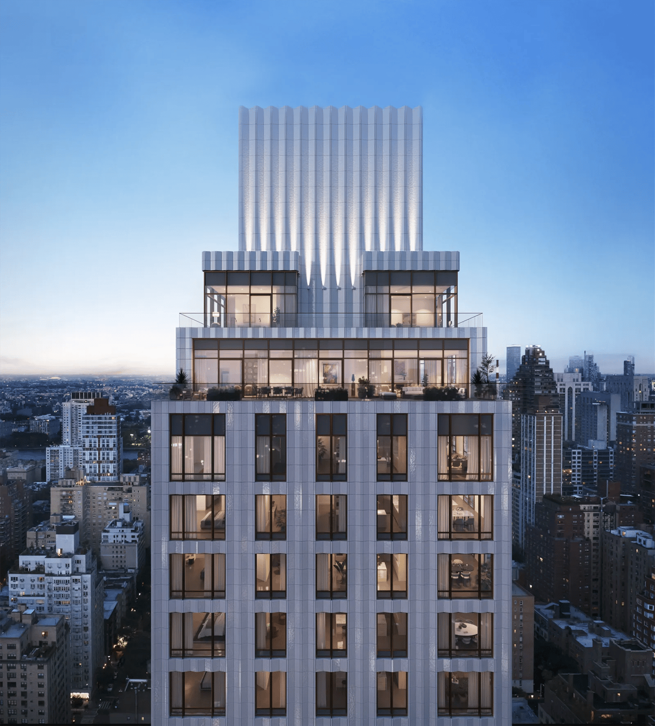 Modern residential tower with a sculptural white crown and illuminated terraces above the city at dusk.