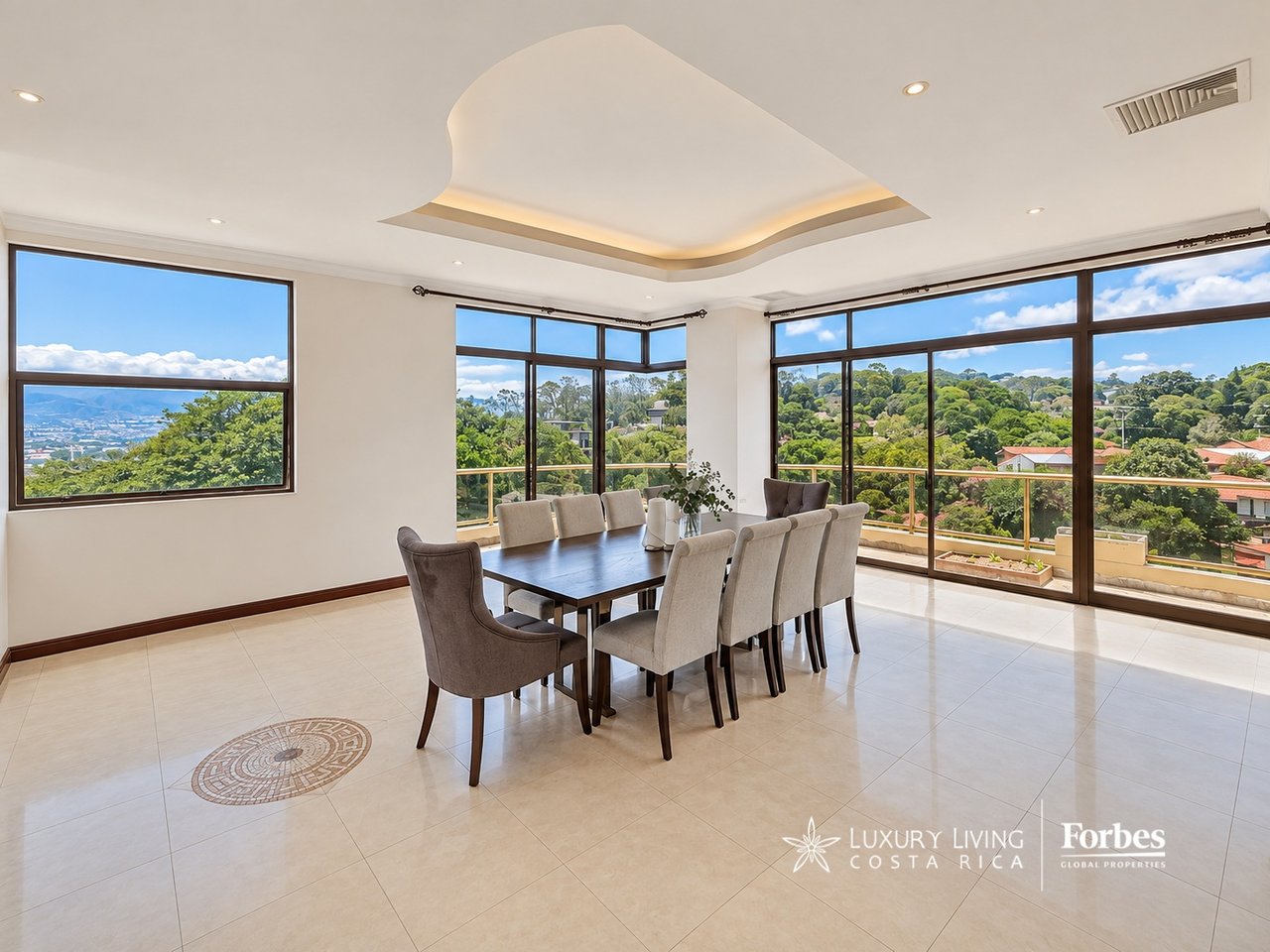 Dining room with a long table beside floor-to-ceiling windows overlooking wooded hills and distant mountains.
