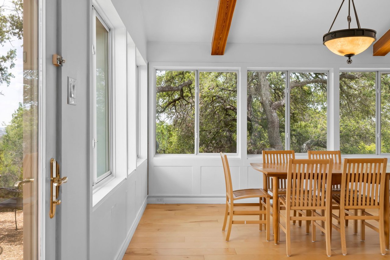 Entry foyer and dining nook with picture windows overlooking mature oak trees at 3935 Lago Vista Drive, a hilltop Mid-Century Modern home near Lake Travis, Austin, TX.