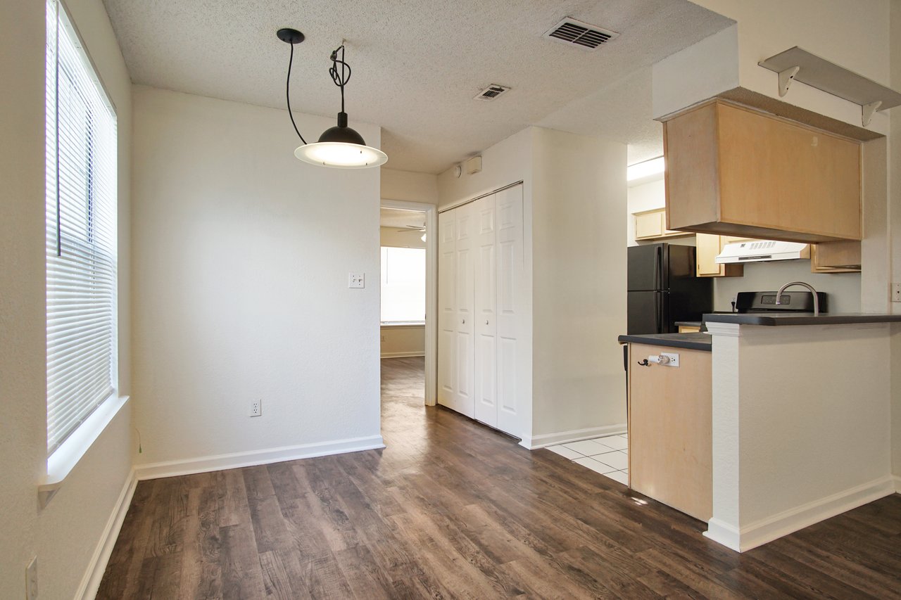 A cozy kitchen and living room area featuring modern decor and warm lighting, creating an inviting atmosphere.