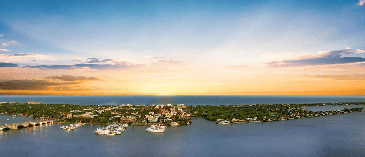 Aerial view of waterfront homes and marinas beside the ocean at sunset.
