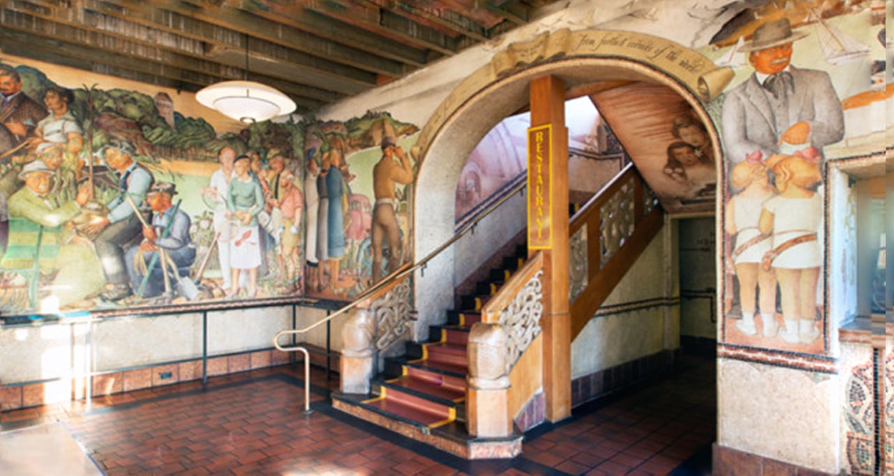 Curved staircase beneath historic murals inside San Francisco landmark building