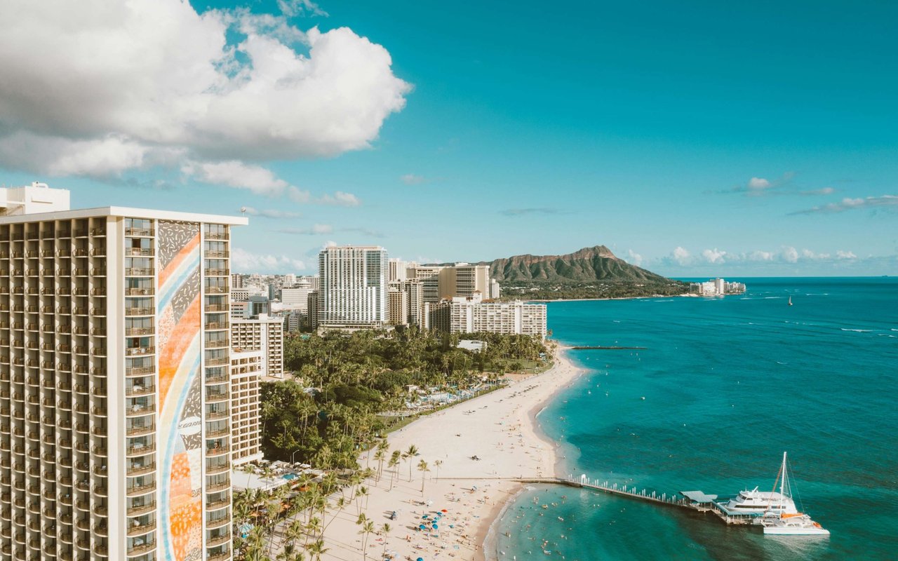 Waikiki Beach curves along turquoise water beneath Diamond Head, with hotels lining the shore.
