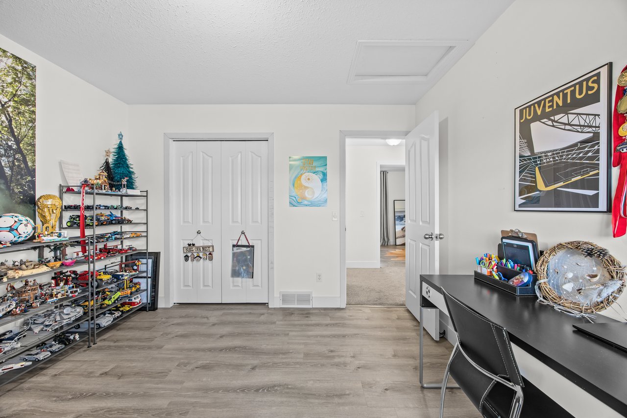 Multipurpose room with toy display shelves, a black desk, and a Juventus poster.