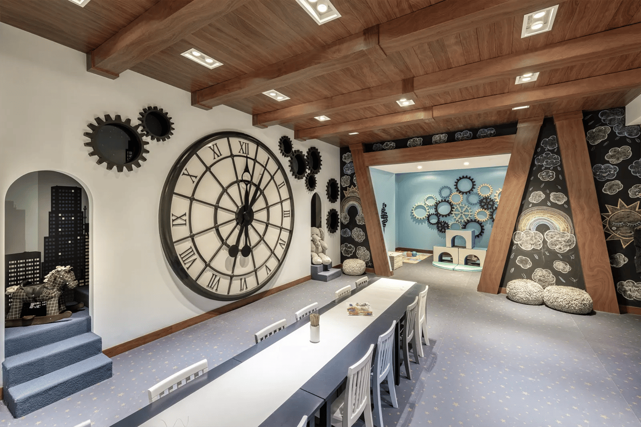 Children’s playroom with a giant Roman numeral clock, gear decorations, and a long communal table.