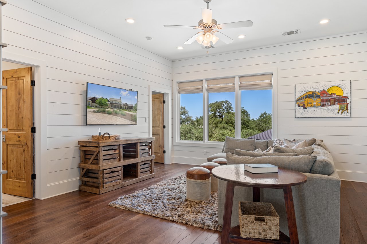 Flex room at 335 Winning Colors with shiplap walls, a ceiling fan, and a comfortable sectional, ideal as a media room or den.