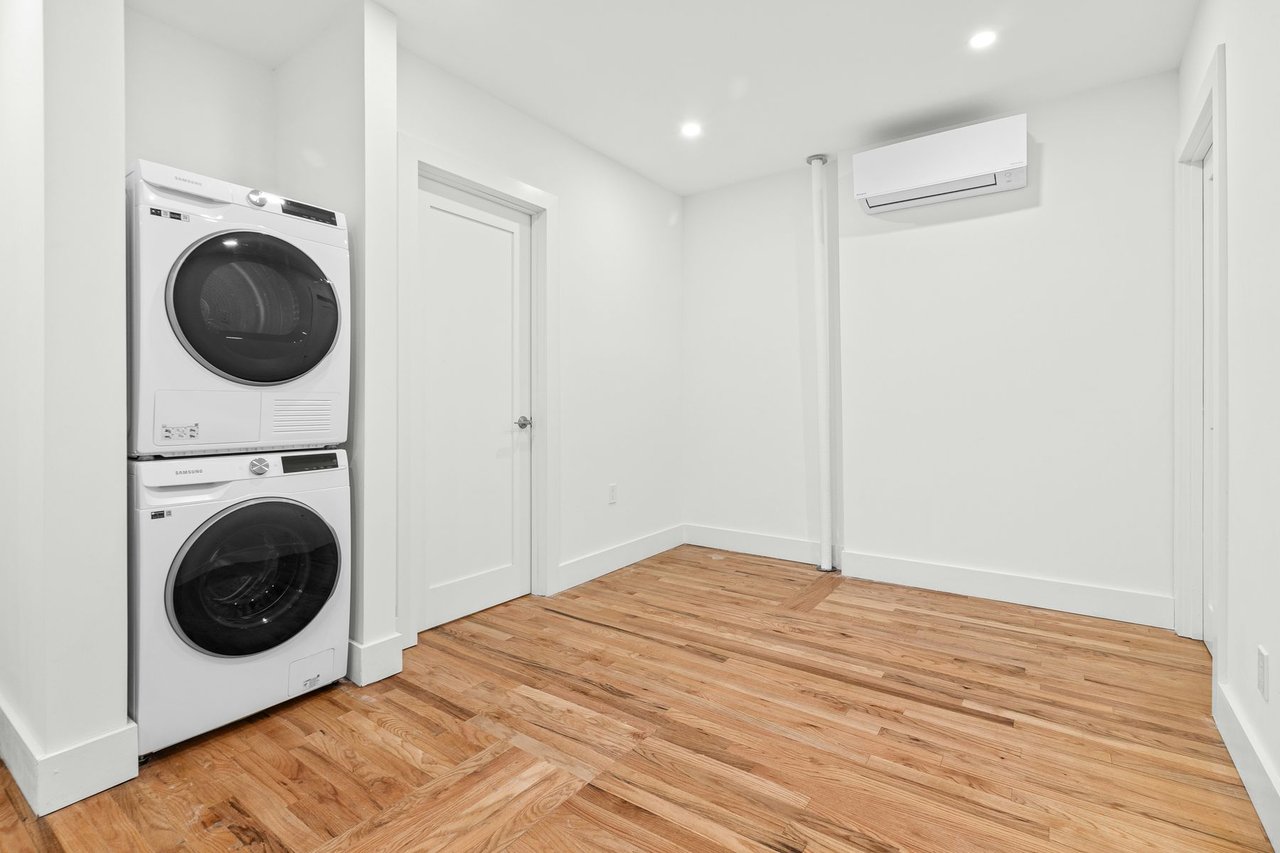 Stacked washer and dryer in a bright apartment with hardwood floors