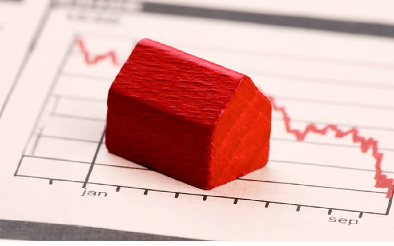 Red model house on a chart with a declining red line.