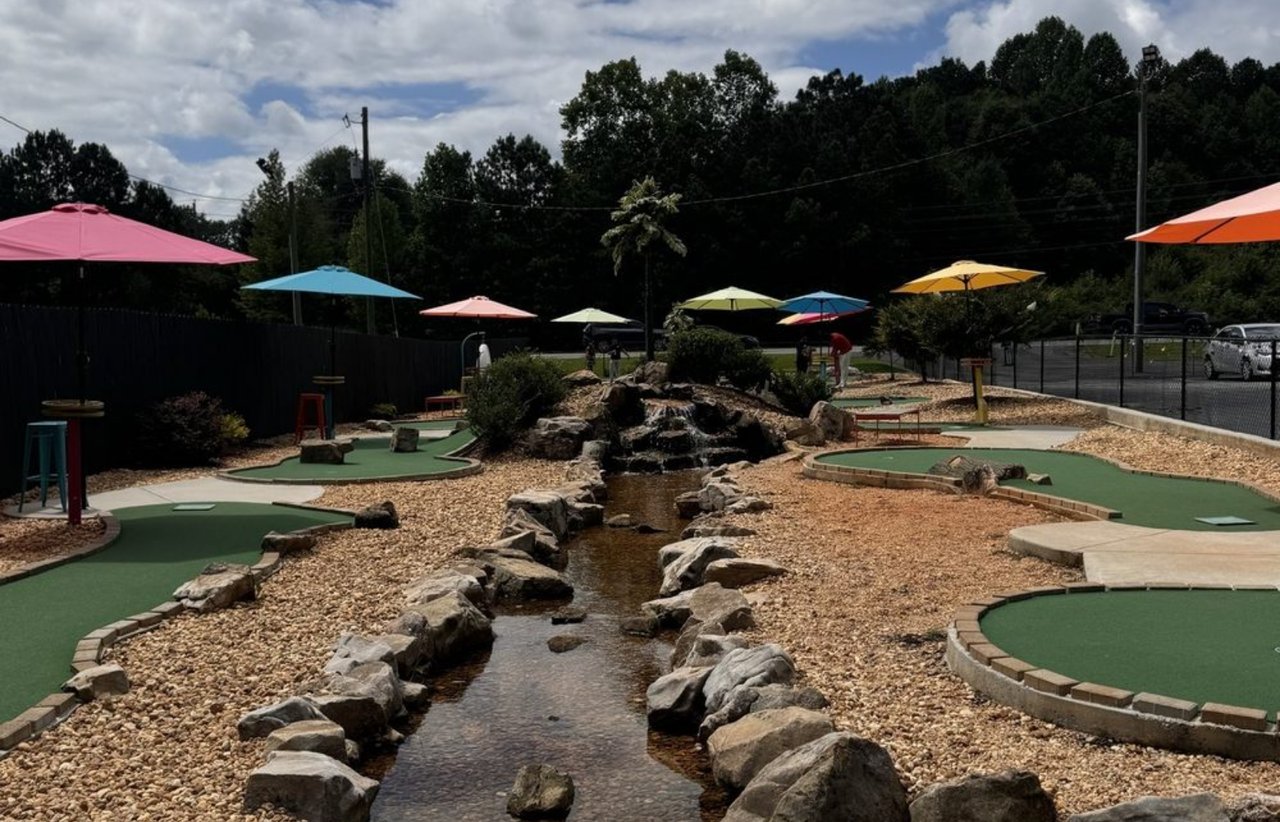 Miniature golf course with colorful umbrellas and a rock-lined stream.