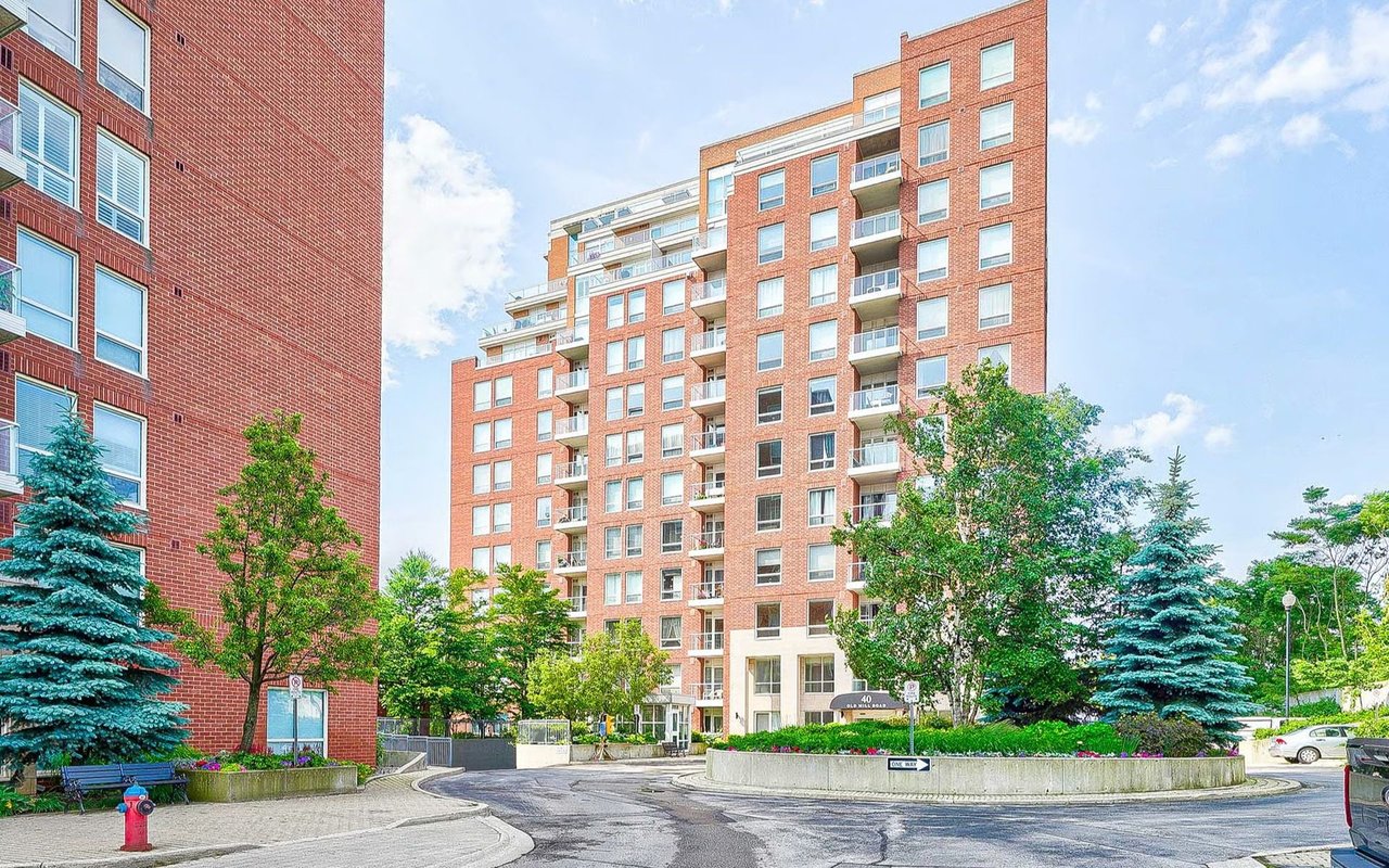 Red-brick condominium with balconies, landscaped grounds, and a circular driveway.