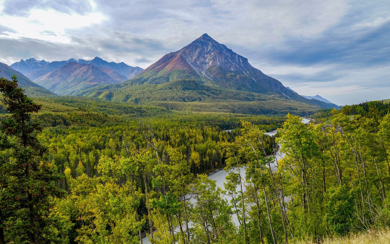 Mountain peak above an autumn forest and winding river.