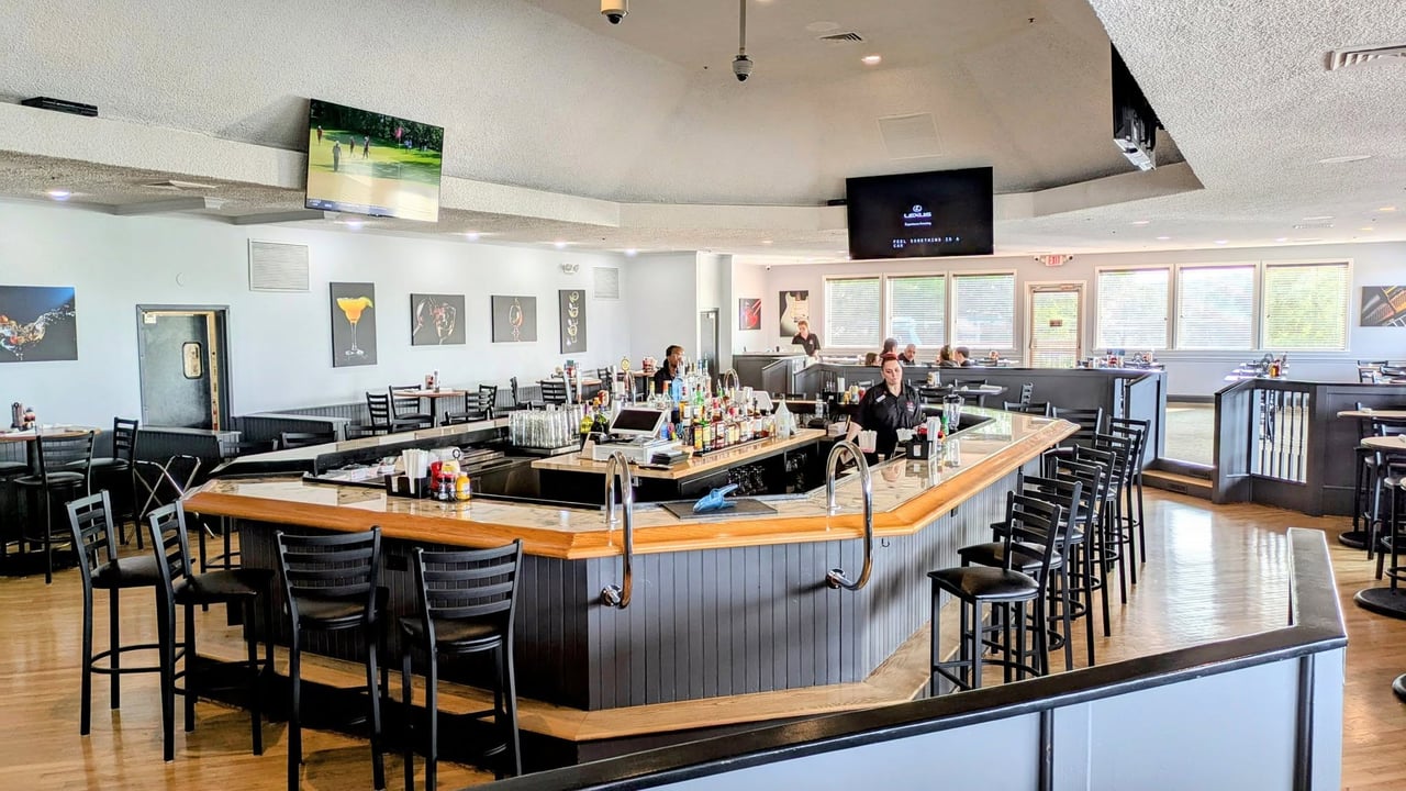 Bar and dining room with a wraparound counter, black stools, and windows.