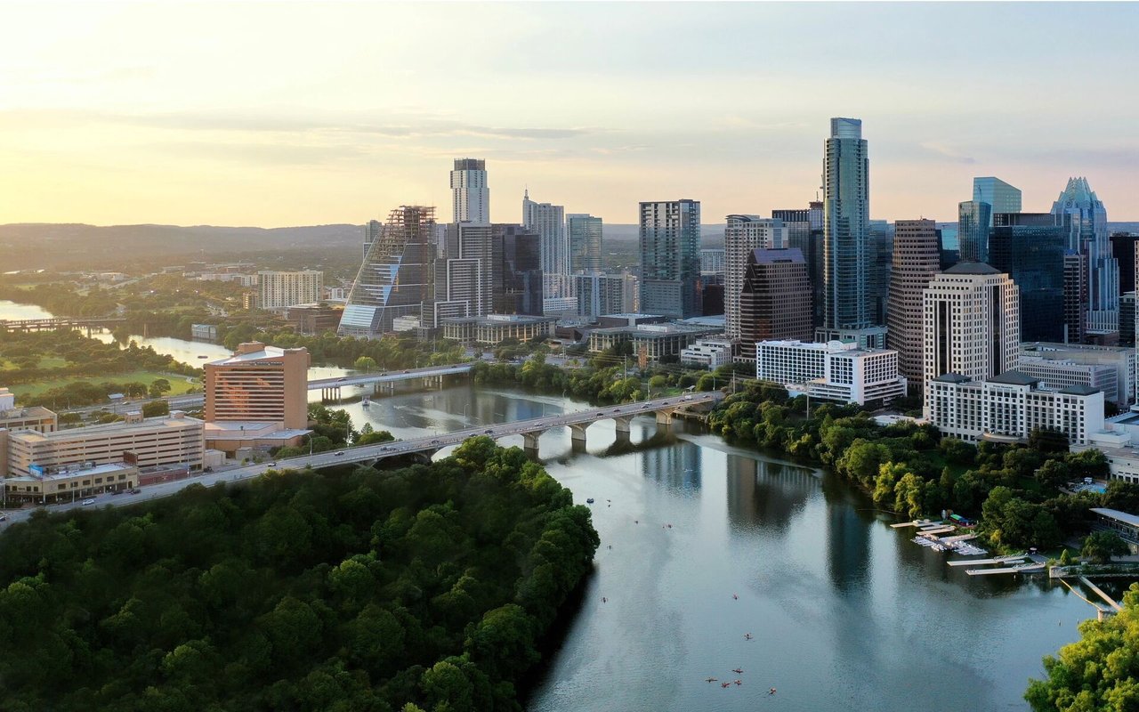 Austin skyline and Colorado River at golden hour, with bridges crossing the water.