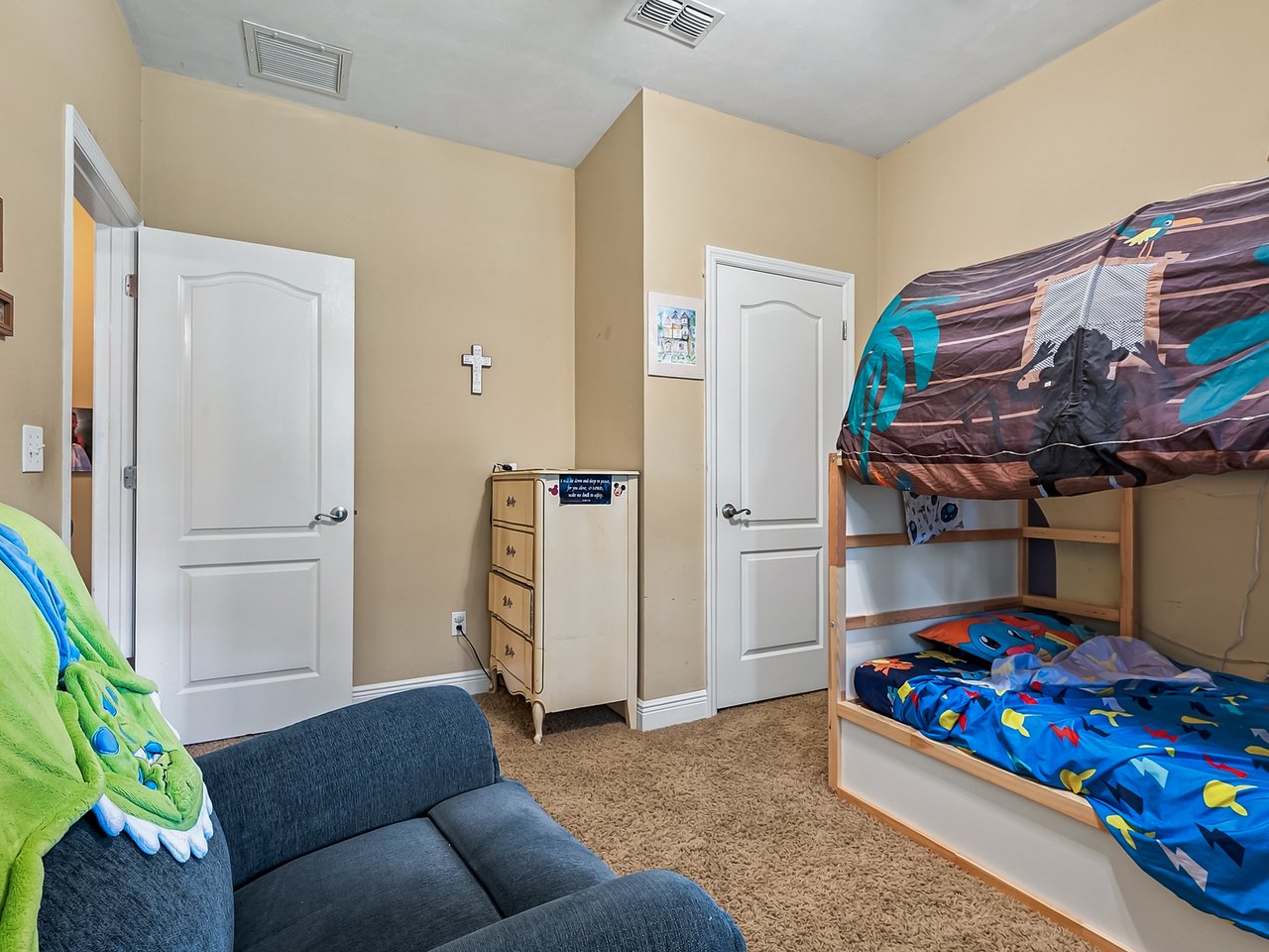 Bedroom with a character-themed bunk bed, blue sofa, and green plush toy.