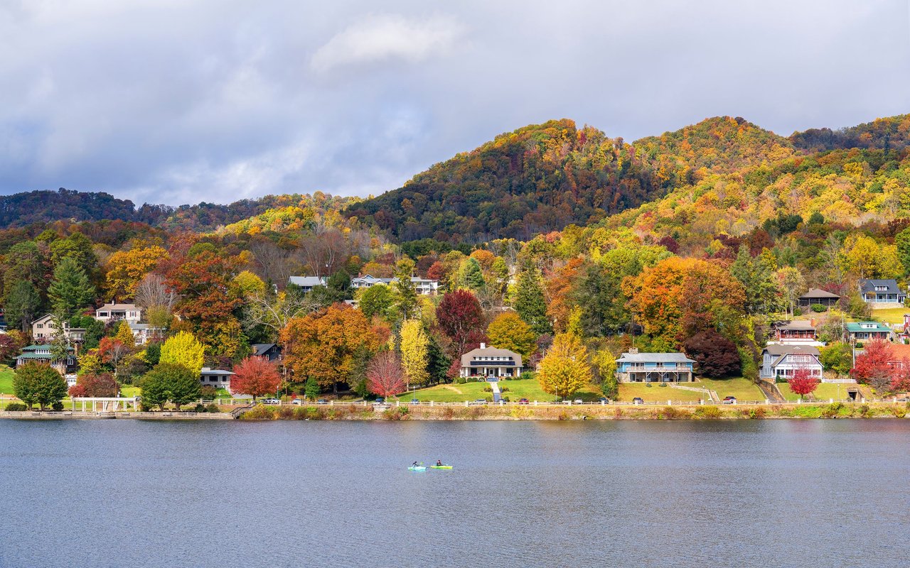 North Asheville homes line the water beneath colorful autumn mountains.