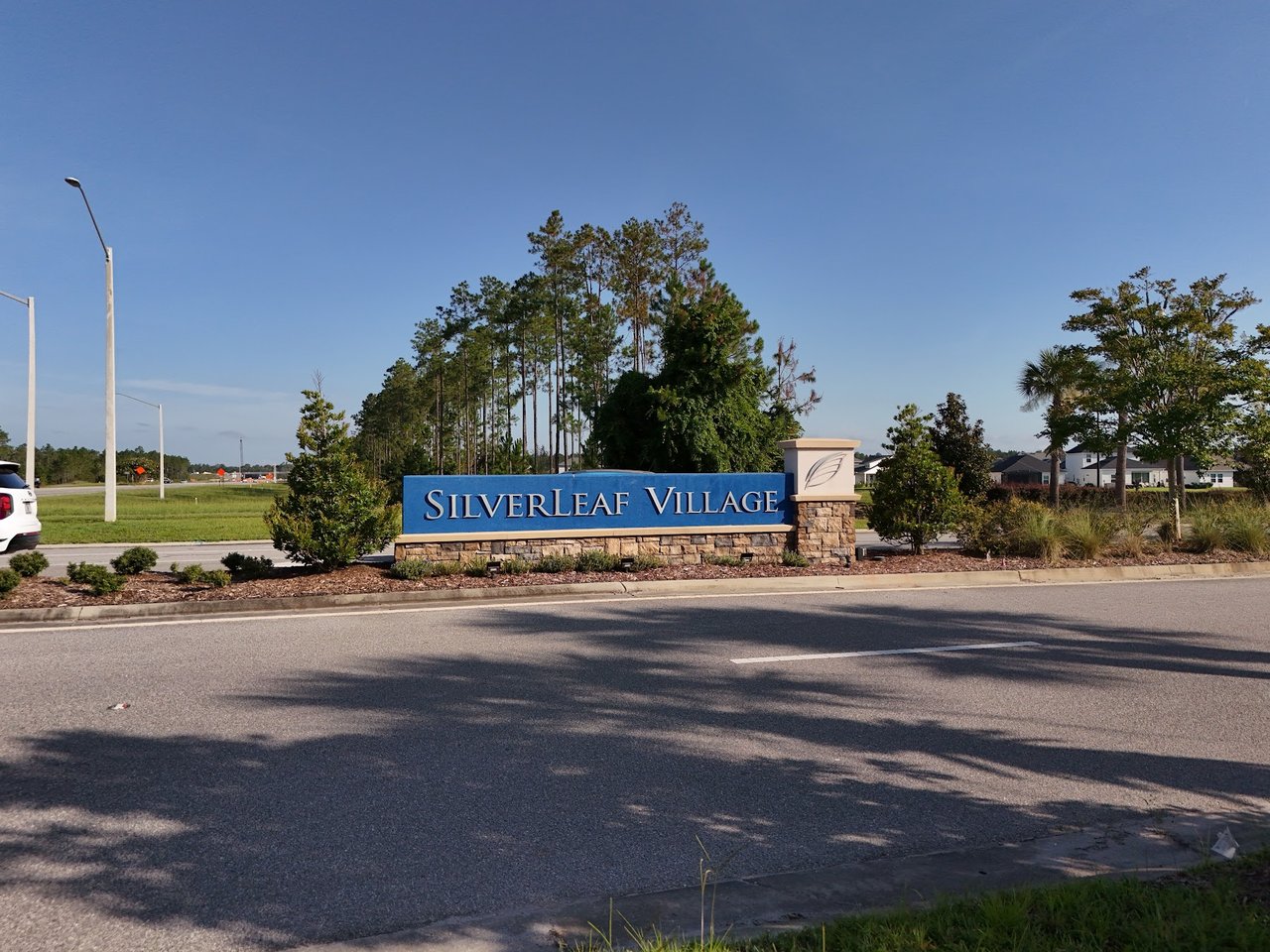 Silverleaf Village entrance sign beside a landscaped road, with trees and homes in the background.
