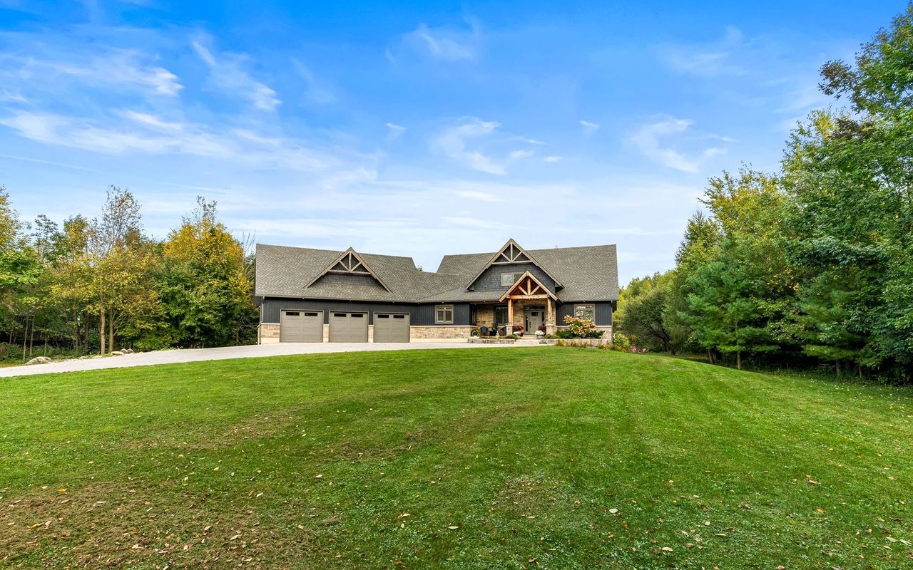 Home with a three-car garage and timber-trimmed gables, set behind a broad lawn and mature trees.