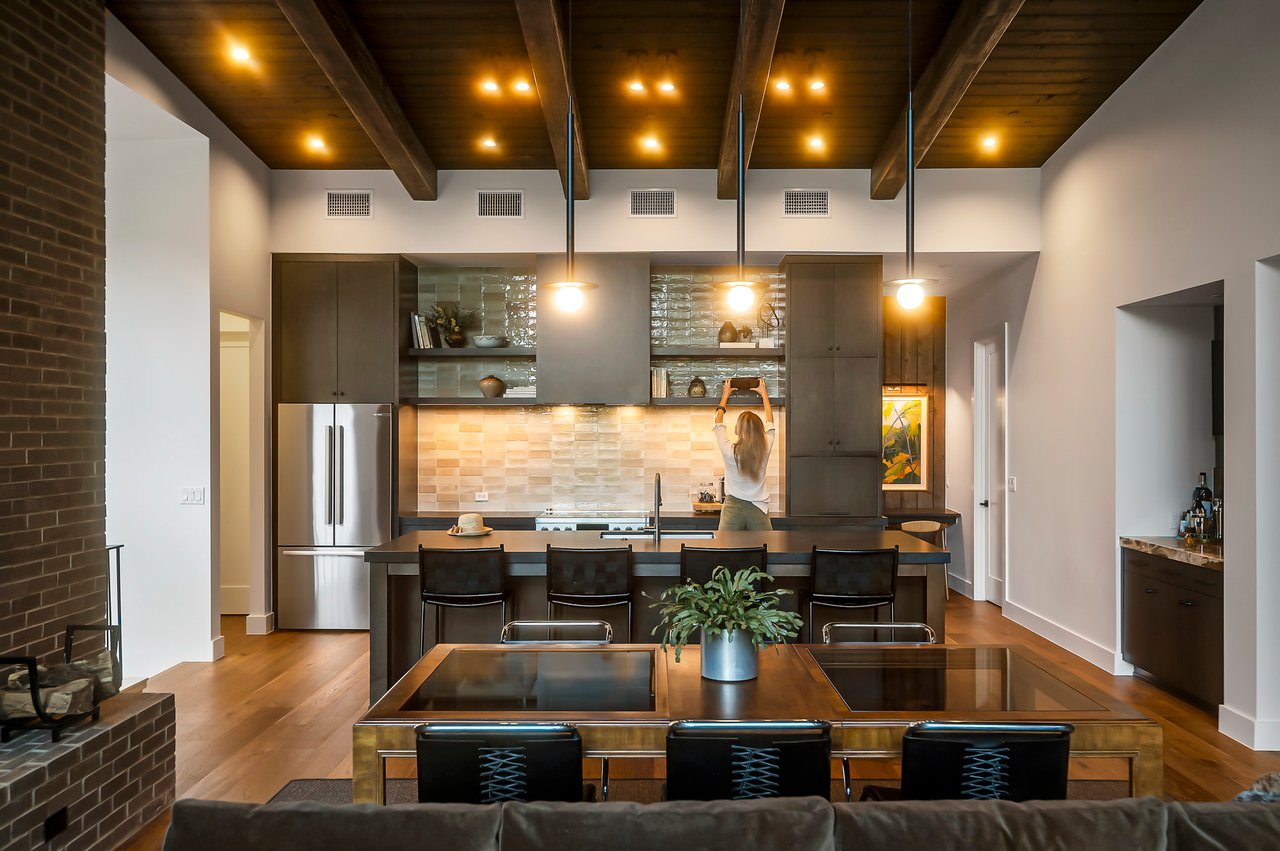 Chef's kitchen with tile backsplash, island seating and exposed beams, cabinetry by Austin Wood Works. Lake Austin waterfront at 2403 Big Horn Drive, Austin.