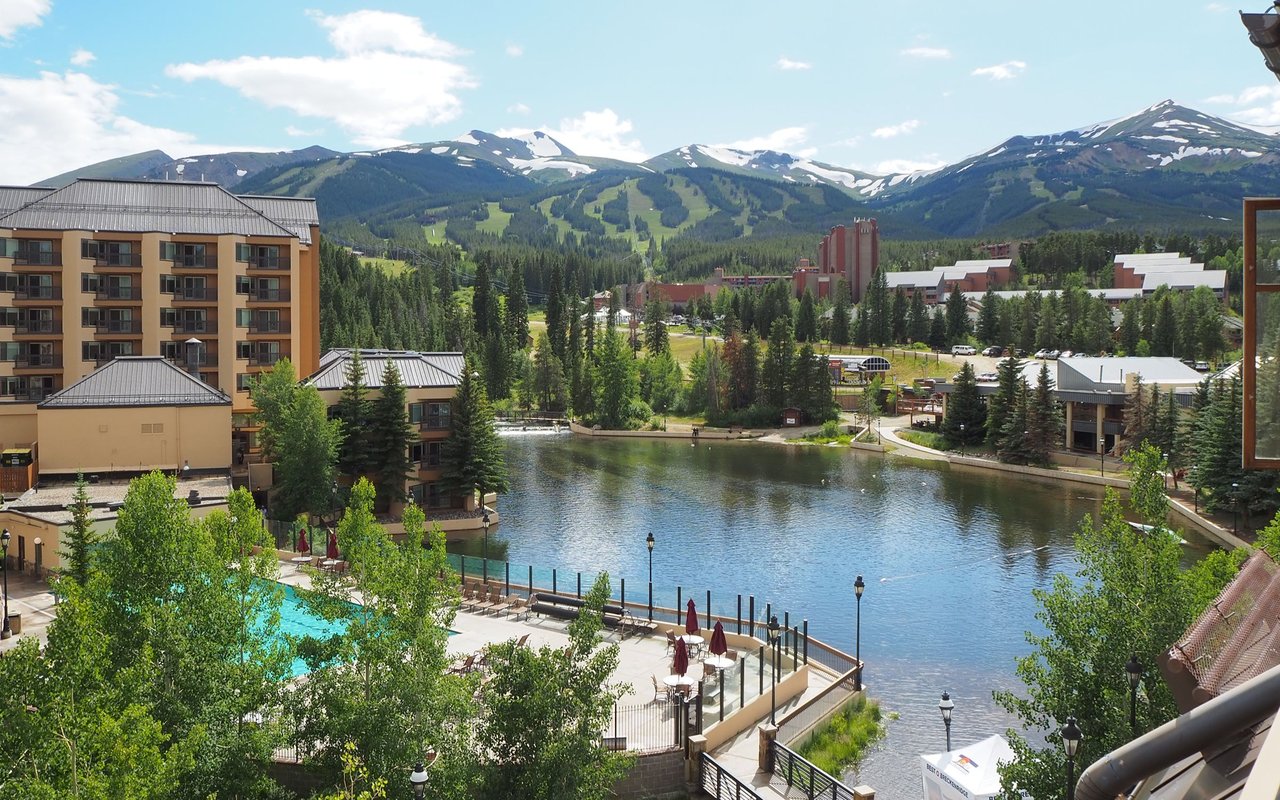 Breckenridge pond and resort buildings beneath snow-patched mountains