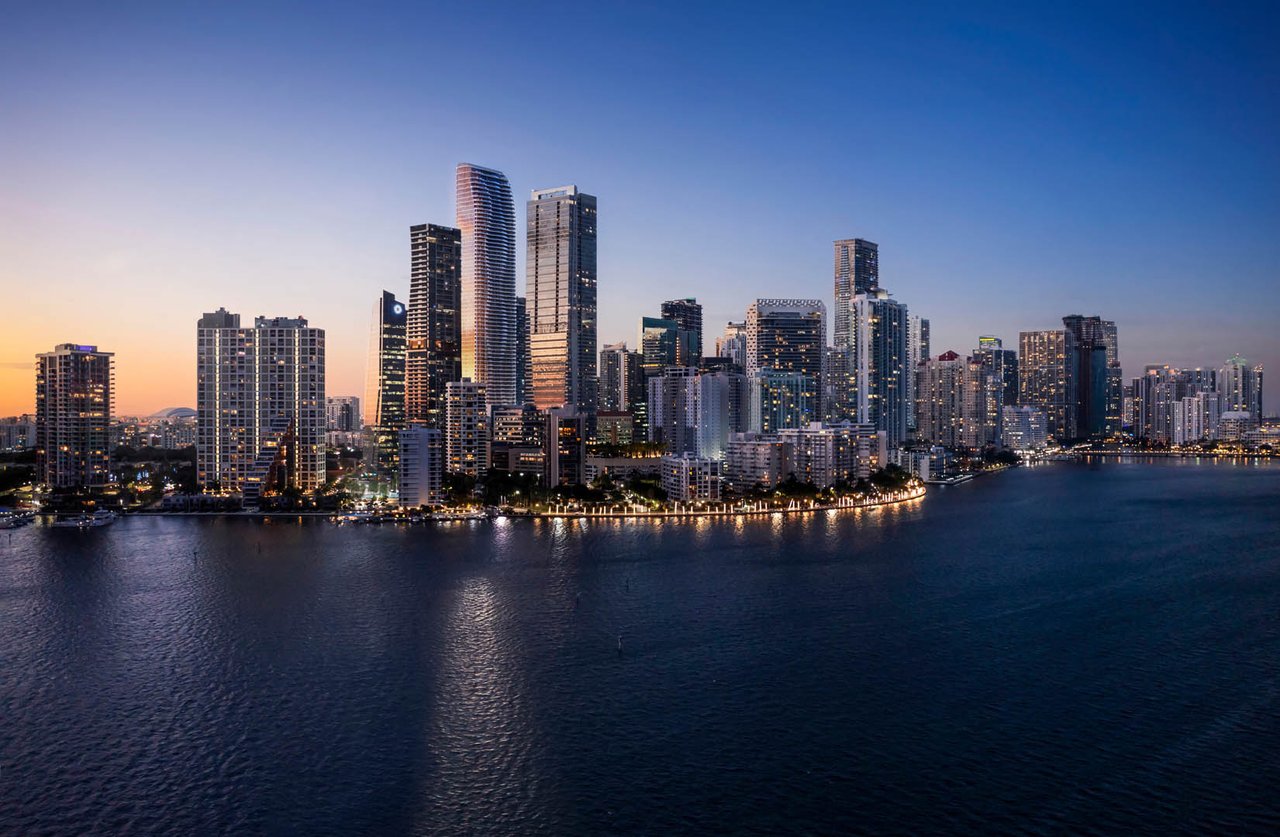 Brickell waterfront skyline at dusk, with illuminated high-rises reflected across the bay.