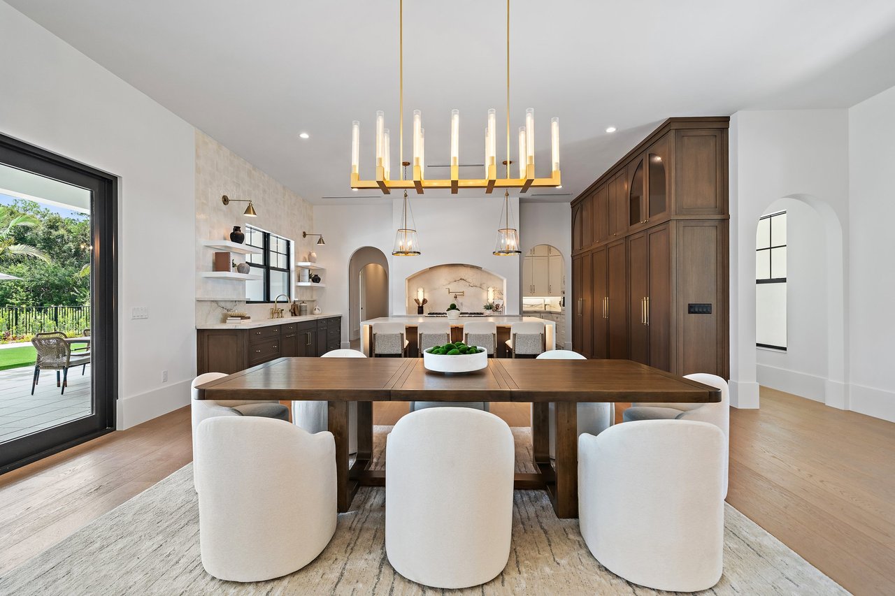 Open-plan kitchen and dining area with dark wood cabinetry, a long dining table, and patio doors.