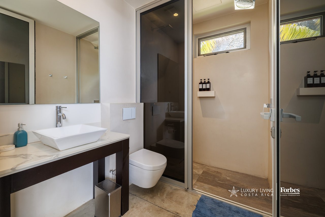 Modern bathroom with a vessel sink, wall-mounted toilet, and glass-enclosed shower.