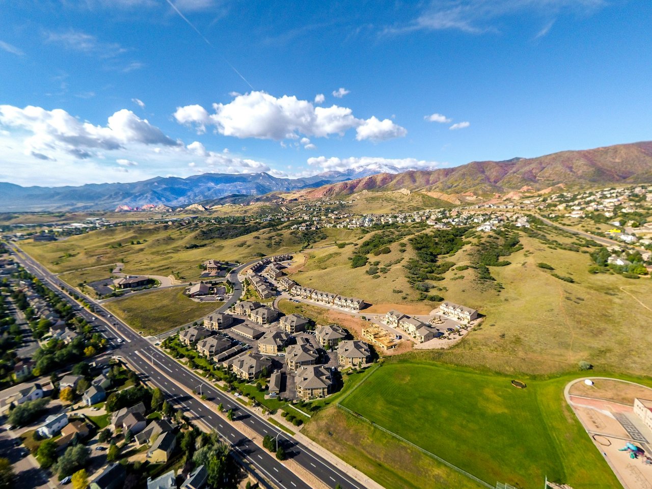 Aerial view of homes and open hills with the Colorado mountains in the distance.
