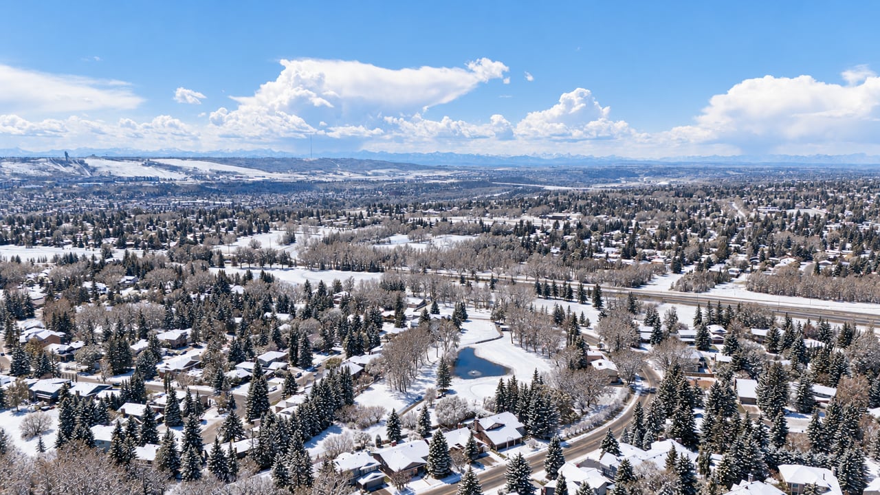 Seasonally edited aerial view of Varsity, Calgary, with snow-covered homes, trees and green space