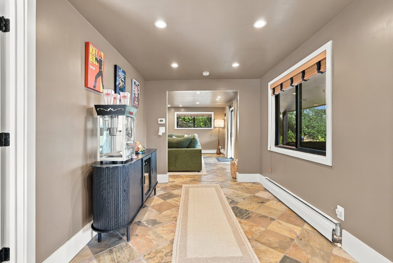 Furnished hallway with multicolored tile flooring, a popcorn machine, and a view into a sitting room.
