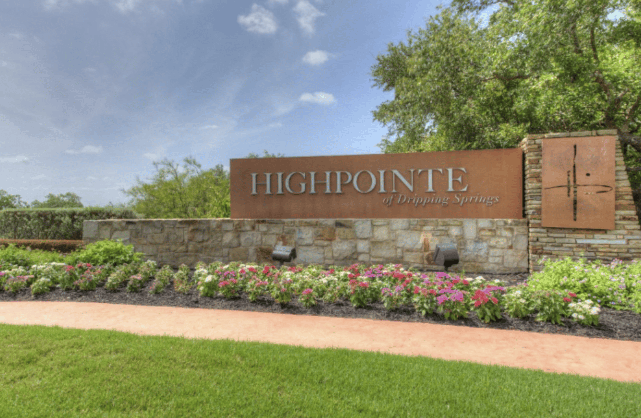 Highpointe of Dripping Springs neighborhood entrance sign with stonework and flower beds.